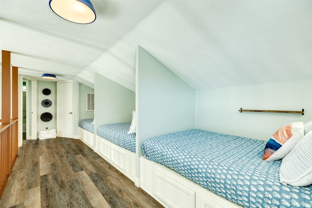 bedroom with vaulted ceiling, a textured ceiling, and wood finished floors