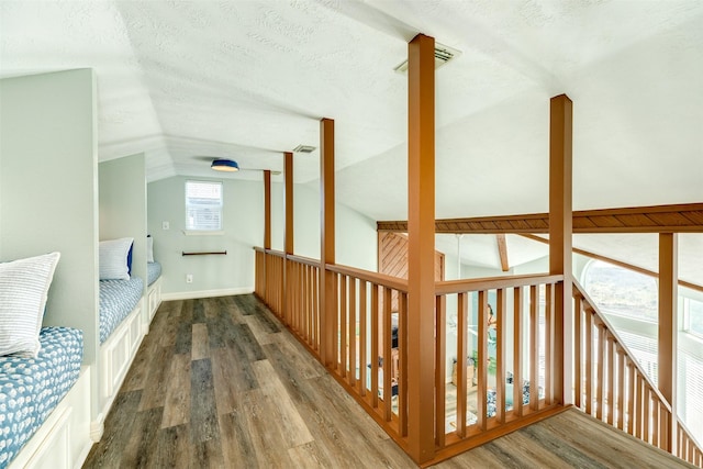 interior space featuring lofted ceiling, a textured ceiling, visible vents, and wood finished floors