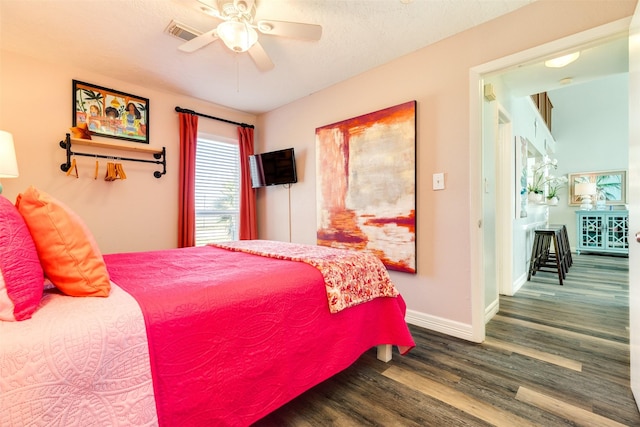 bedroom with a textured ceiling, wood finished floors, a ceiling fan, visible vents, and baseboards