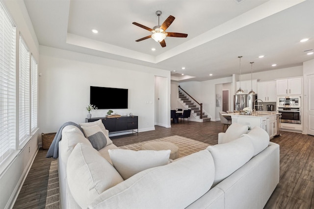 living room featuring dark wood-style floors, recessed lighting, a raised ceiling, and stairway