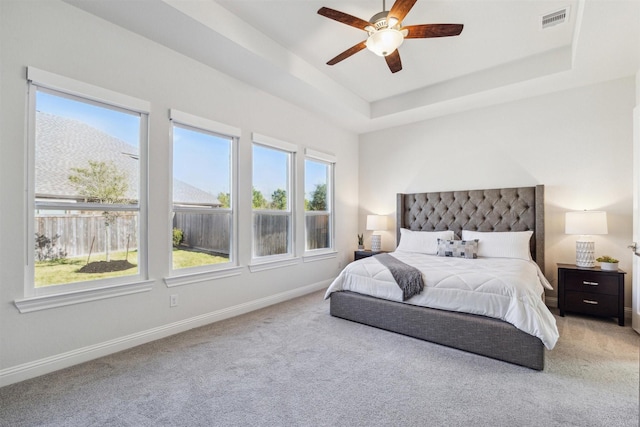 bedroom featuring a raised ceiling, visible vents, light carpet, and baseboards