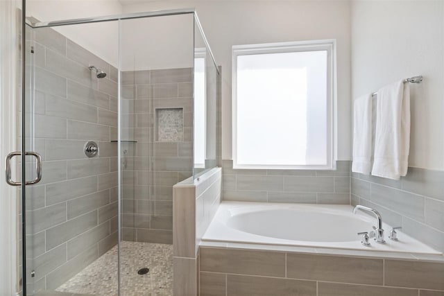 bathroom featuring a stall shower and a bath