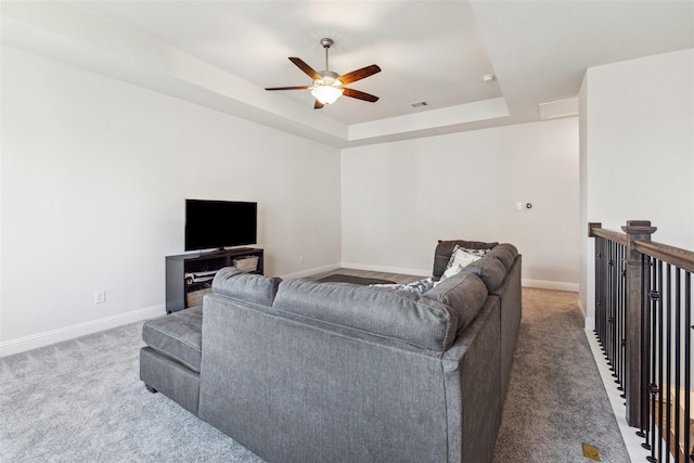 living room with visible vents, baseboards, a raised ceiling, a ceiling fan, and carpet