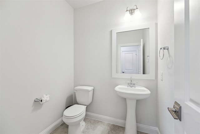 half bathroom featuring toilet, baseboards, and tile patterned floors