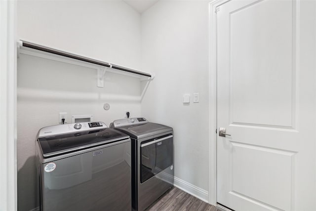 clothes washing area featuring wood finished floors, laundry area, baseboards, and separate washer and dryer