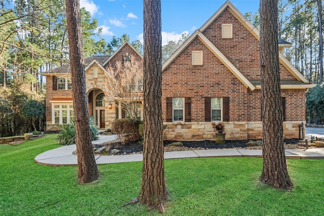 view of front of property with stone siding, brick siding, and a front lawn