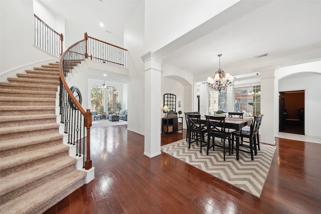 dining room featuring a chandelier, wood-type flooring, decorative columns, and baseboards