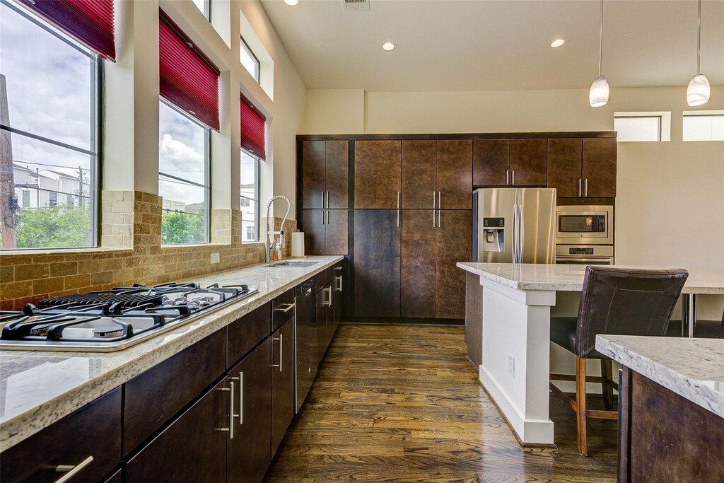 1620 Alamo St, Houston, TX 77007 - kitchen featuring dark brown cabinetry, dark wood finished floors, decorative backsplash, stainless steel appliances, and a sink