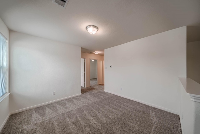 carpeted spare room featuring baseboards and visible vents