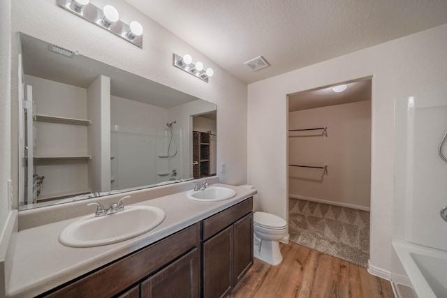 full bath featuring a spacious closet, wood finished floors, a sink, and visible vents