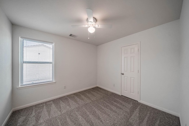 carpeted spare room featuring a ceiling fan, visible vents, and baseboards