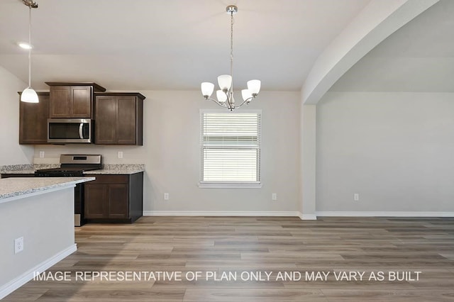 kitchen featuring lofted ceiling, light wood-style flooring, appliances with stainless steel finishes, and dark brown cabinets