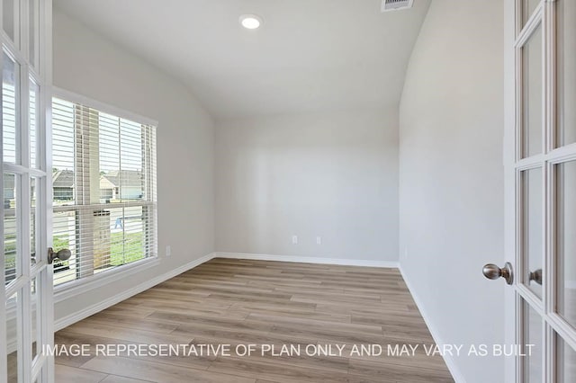 empty room with lofted ceiling, light wood-style floors, baseboards, and french doors