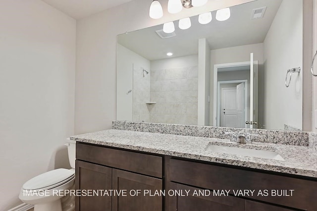 bathroom with visible vents, vanity, toilet, and tiled shower