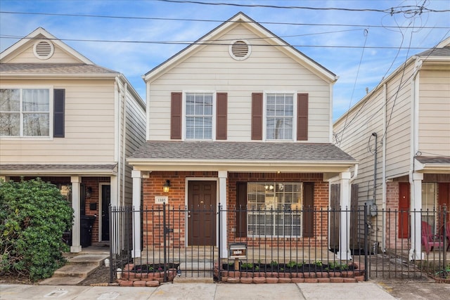 traditional home featuring a porch, a shingled roof, and brick siding