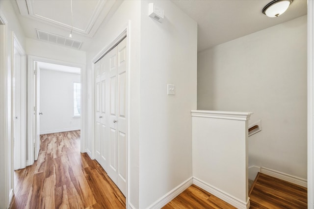 hallway with baseboards, wood finished floors, visible vents, and attic access