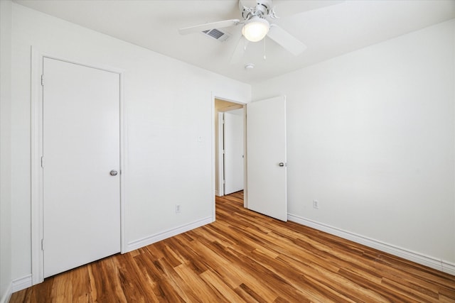 unfurnished bedroom with baseboards, visible vents, ceiling fan, and wood finished floors