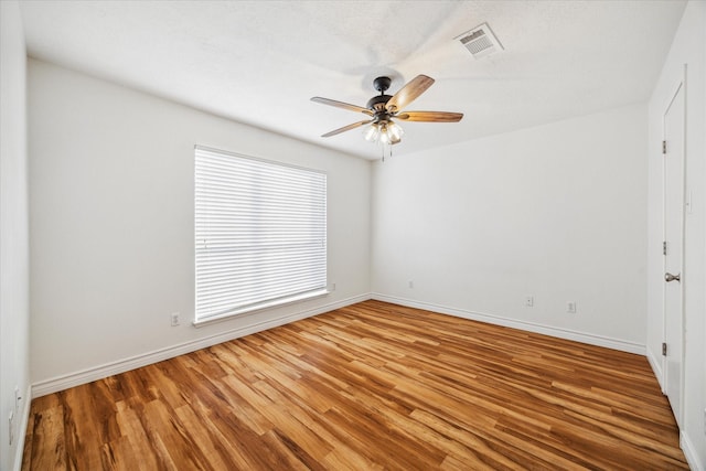 unfurnished room featuring baseboards, ceiling fan, visible vents, and wood finished floors