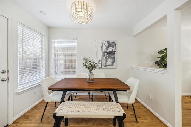 dining space featuring light wood-type flooring and baseboards