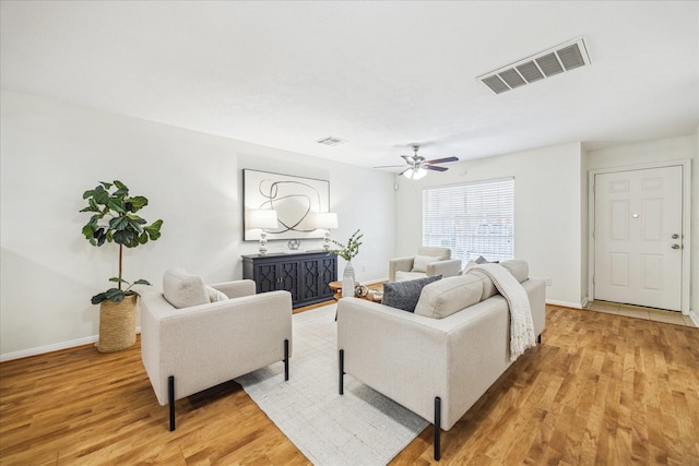 living area featuring light wood-type flooring, baseboards, visible vents, and a ceiling fan