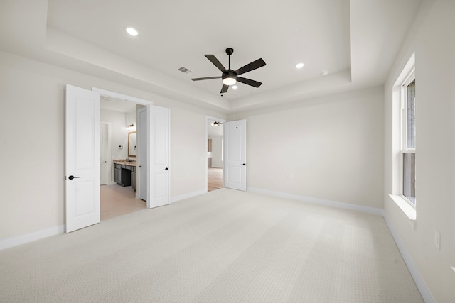 9975 Monarch Landing Cv, Willis, TX 77318 - unfurnished bedroom with a raised ceiling, light carpet, baseboards, recessed lighting, and ensuite bath