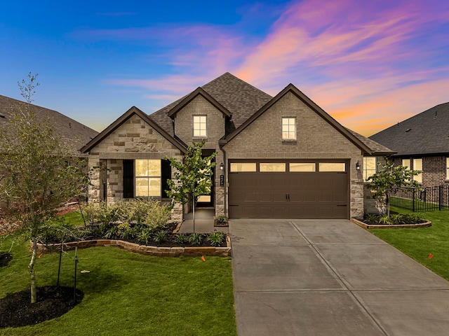 9975 Monarch Landing Cv, Willis, TX 77318 - french country inspired facade featuring driveway, stone siding, an attached garage, and roof with shingles