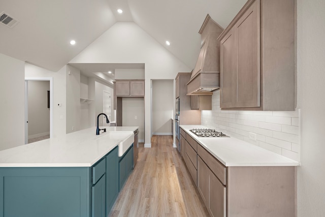 9975 Monarch Landing Cv, Willis, TX 77318 - kitchen with a sink, premium range hood, appliances with stainless steel finishes, light wood-style floors, and tasteful backsplash