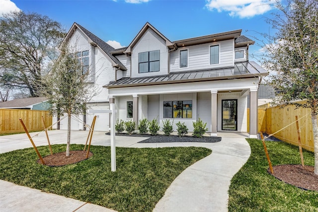 modern farmhouse style home featuring a standing seam roof, fence, concrete driveway, and an attached garage