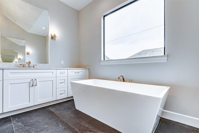 bathroom with lofted ceiling, baseboards, a freestanding bath, and vanity