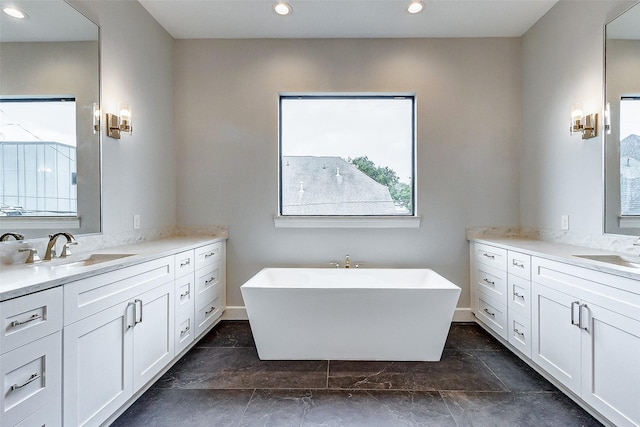 full bathroom featuring a freestanding tub, two vanities, a sink, and recessed lighting