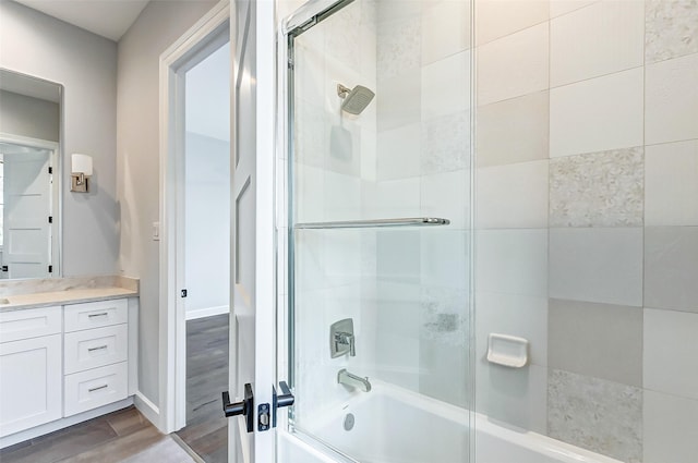 full bath with bath / shower combo with glass door, vanity, baseboards, and wood finished floors