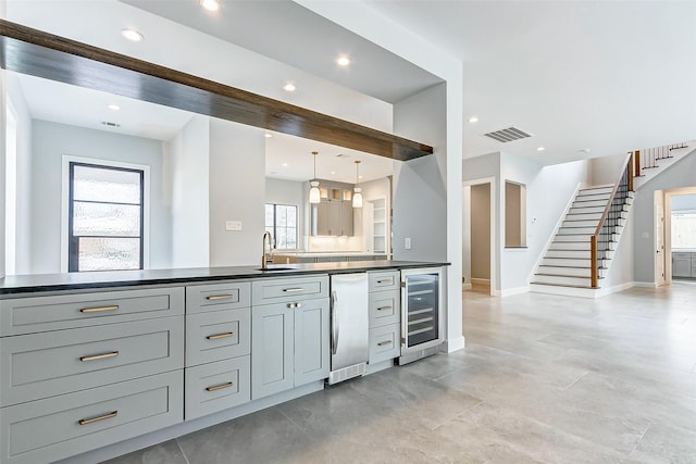 kitchen with wine cooler, a sink, visible vents, gray cabinets, and dark countertops