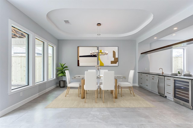 dining room featuring beverage cooler, visible vents, a raised ceiling, and baseboards