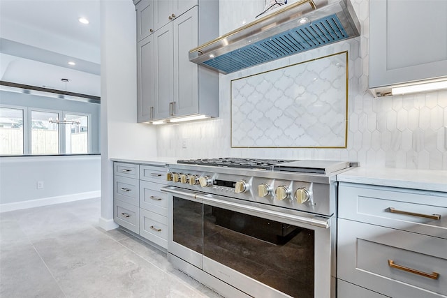 kitchen featuring range hood, stainless steel range, light countertops, decorative backsplash, and gray cabinetry