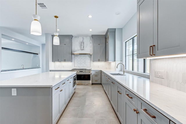 kitchen with high end stainless steel range, gray cabinets, visible vents, backsplash, and premium range hood