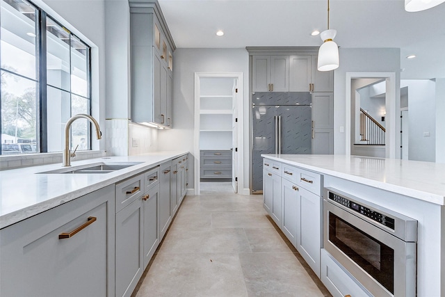 kitchen featuring recessed lighting, gray cabinets, a sink, and built in appliances