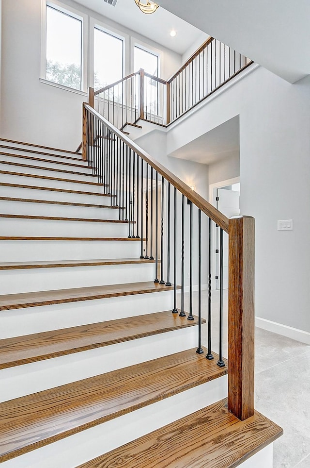 staircase with a towering ceiling, visible vents, baseboards, and recessed lighting