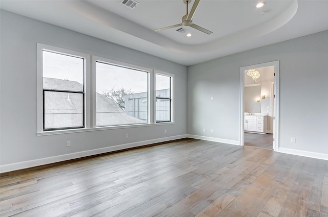 spare room with baseboards, ceiling fan, wood finished floors, a tray ceiling, and recessed lighting