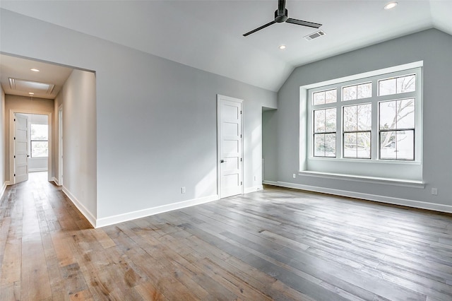 empty room with a ceiling fan, visible vents, vaulted ceiling, and hardwood / wood-style flooring