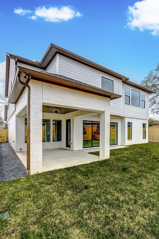 back of house featuring ceiling fan, a patio, brick siding, fence, and a lawn