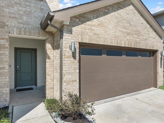 exterior space with an attached garage, concrete driveway, and brick siding