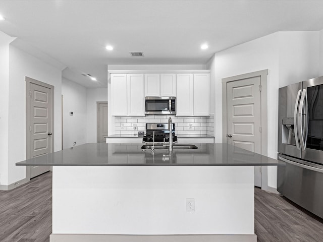 kitchen featuring appliances with stainless steel finishes, dark wood-type flooring, backsplash, and white cabinets