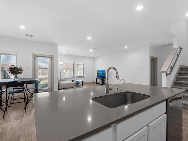 kitchen featuring dark countertops, dishwasher, visible vents, and a sink