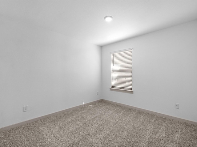 carpeted spare room featuring baseboards