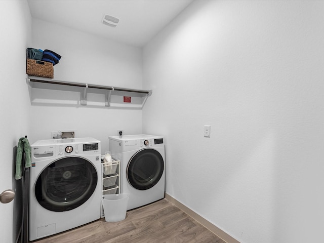 laundry area with washing machine and dryer, laundry area, wood finished floors, visible vents, and baseboards