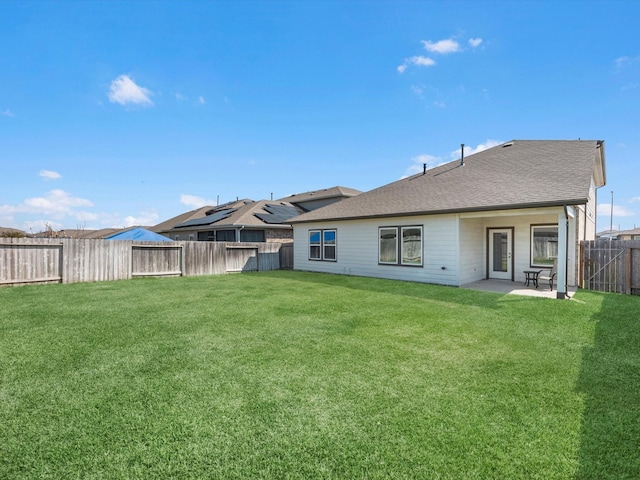 back of property featuring a shingled roof, a fenced backyard, a yard, and a patio