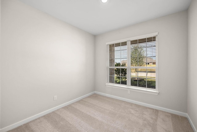 carpeted spare room featuring baseboards