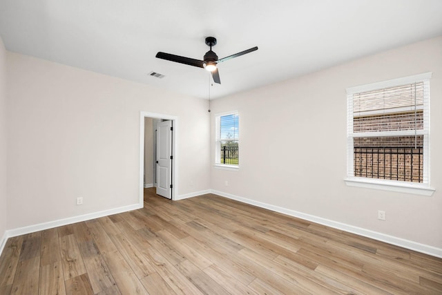 empty room featuring ceiling fan, wood finished floors, visible vents, and baseboards