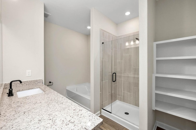 full bath featuring visible vents, wood finished floors, a garden tub, a shower stall, and a sink