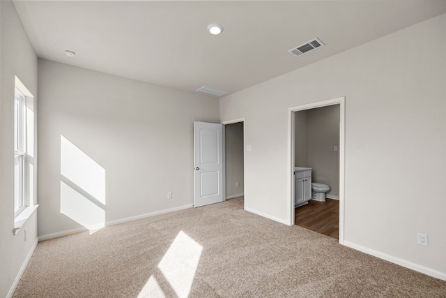 unfurnished bedroom featuring carpet flooring, connected bathroom, visible vents, and baseboards